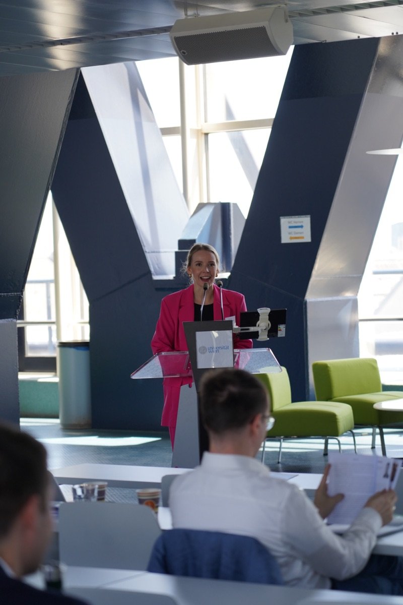 Vortragende in pinkem Blazer bei einer Konferenz